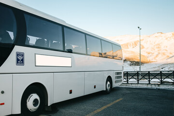 White Bus Parked Against Snowy Mountain Background. Blank White Advertising Billboard 