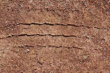 Close up textured abstract background of imprinted tire tyre tracks on a dirt surface