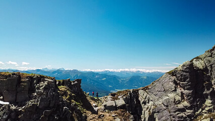 Hiker couple on top of mount Boese Nase, Ankogel Group, Carinthia, Austria. panoramic view of majestic Julian Alps and Karwanks. Idyllic hiking trail in remote Austrian Alps in summer. Rugged terrain
