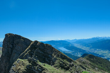 Idyllic hiking trail on alpine meadow with scenic view of lake Millstatt seen from mountain peak Boese Nase in Ankogel Group, Carinthia, Austria. Remote landscape in majestic Austrian Alps in summer