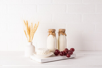 Fresh dairy products on a white wooden board and a vase with ears of corn on a wooden table....