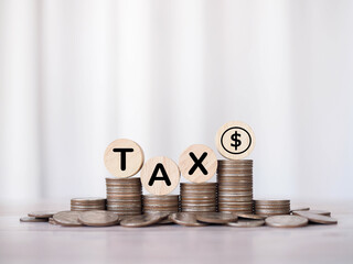 Wooden blocks with the word TAX on stack of coins and Dollar coin icon. The concept of saving money for payment tax in future