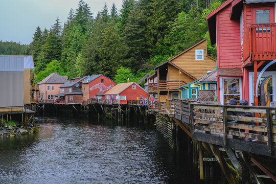 Historic old wooden houses facades along Creek in downtown Ketchikan, Alaska with colorful buildings, fisherman homes, marina with boats and tourist traffic on road popular cruise ship destination