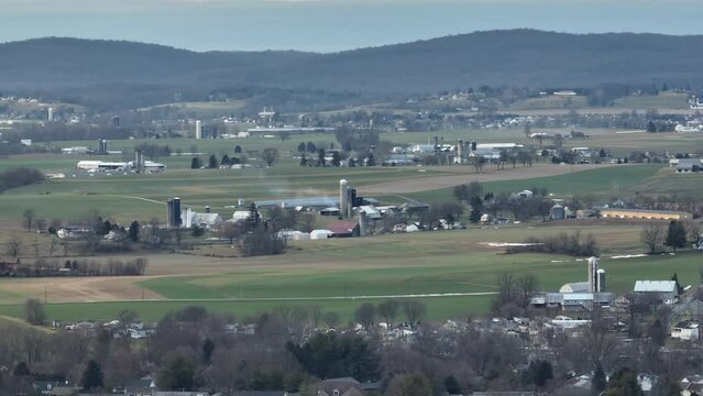 Rolling hills with farms in Pennsylvania during winter. Panning panoramic shot of rural countryside in USA.