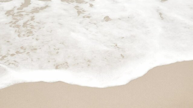 close up to Sea waves rolling over the fine sand beach, waves break on white sand beach with beautiful foam, tropical summer vacation holiday nature background