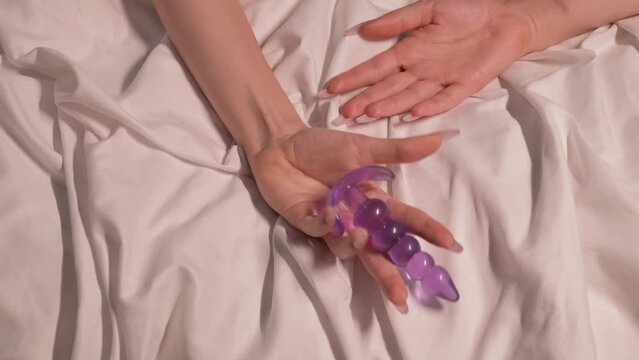 couple has anal sex on the bed using a sex toy for female orgasm and satisfaction. A man gives a woman an butt anal plug in hand on in the bedroom