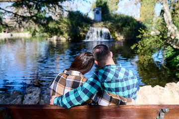 Young couple hugging on a park bench on a sunny day