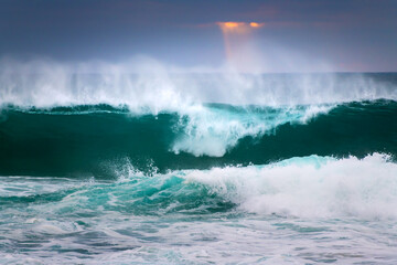 Big ocean waves on the beach at sunset. Atlantic ocean in Nazare, Portugal.
