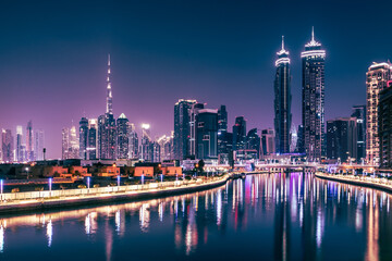 Fototapeta na wymiar Dubai downtown night city skyline. Skyscrapers and lights are reflected in the water canal.