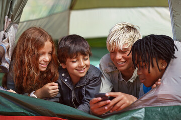 Phone, happy and children in tent for camp networking on social media, mobile app or internet. Smile, technology and young kids bonding, relax and streaming video online with cellphone on vacation.
