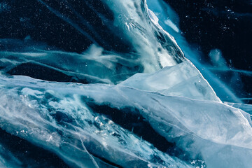 Transparent blue ice with cracks on Baikal lake in winter. Abstract winter nature background.
