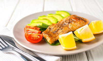 Fried fish with avocado, lemon, herbs and tomatoes on a platter