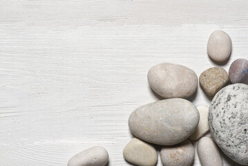 Fototapeta na wymiar Sea pebble stones on the white wooden flat lay table background with copy space.