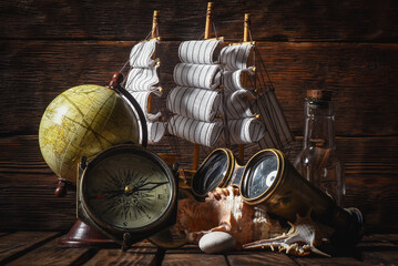Sea travel or piracy concept background. Sea ship boat and compass on the wooden desk table...