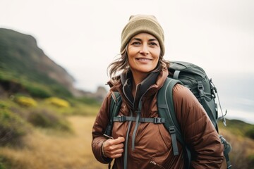 Portrait of a smiling woman with a backpack hiking in the mountains.