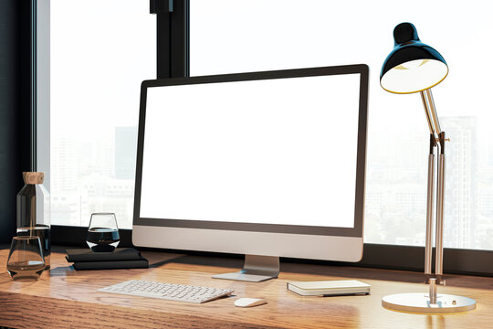 Creative designer desk with empty white computer monitor, lamp, supplies and other items. Window with city view in the background. Mock up, 3D Rendering.