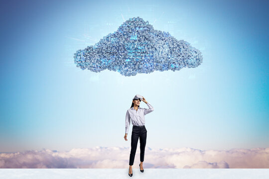 Happy young businesswoman with vr glasses standing under abstract digital cloud with programming language on bright sky background. Digital storage, database, network and technology concept.