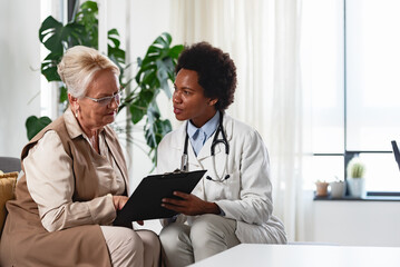 Doctor specialist consulting a patient at the clinic. A female doctor is talking with a female elderly patient.