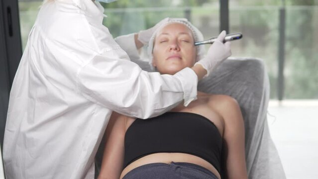 Cosmetologist doing hydrafacial treatment on woman face For rejuvenation