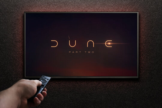 TV screen playing Dune Part Two trailer or movie. Man turns on TV with remote control. Astana, Kazakhstan - May 15, 2023.
