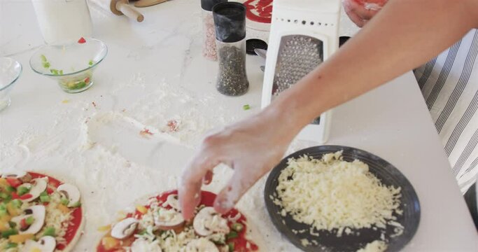 Hands prepare pizza toppings in a home kitchen