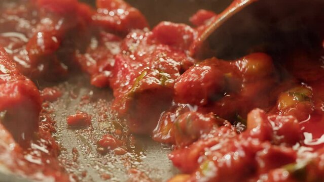 Cooking tomato sauce classic homemade Italian tomato sauce with basil for pasta and pizza in the pan. Chef cooking traditional Italian food.
