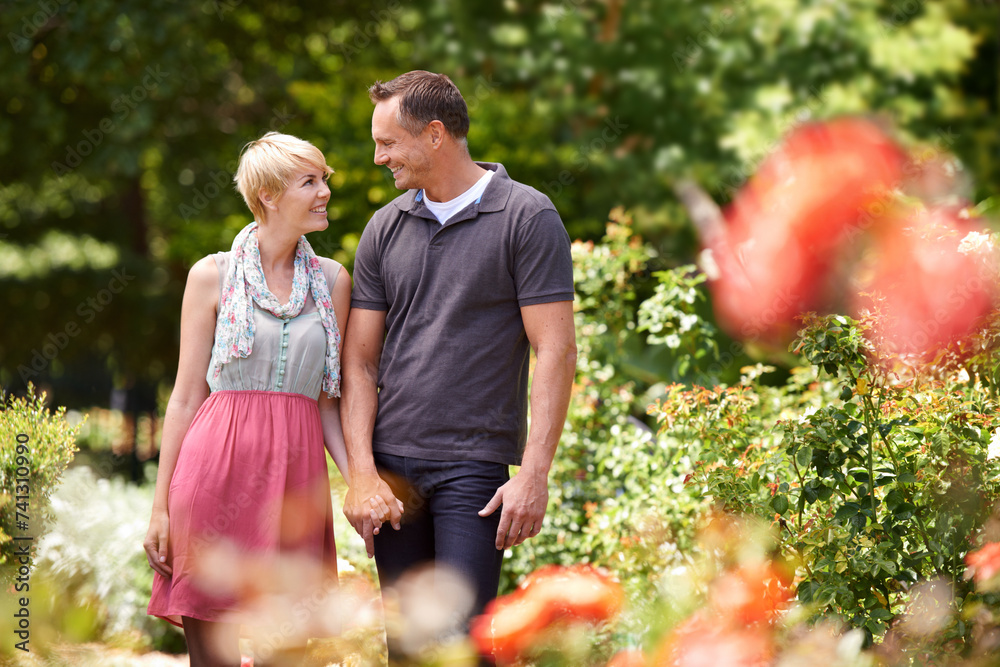 Poster Love, holding hands and couple in a park with care, support and trust while bonding outdoor. Security, travel and people walking in a field of flowers for holiday, vacation or romantic summer date