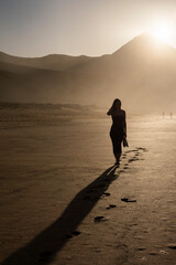 Chica con un vestido caminando por la playa de Cofete en Fuerteventura con los zapatos en la mano