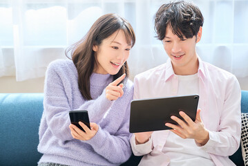 スマートフォンとタブレットPCの画面を見比べる男女