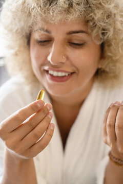 Healthy Diet. Happy Young Woman Holding Omega-3 Capsule, Daily Health Supplement. Young Female Looks At A Golden Omega-3 Capsule in Her Hand. Healthy Lifestyle and Nutritional Supplements.