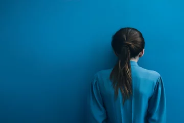 Foto op Plexiglas A woman with psychological problems on her back in front of a blue wall © Rojo