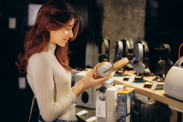 Woman choosing headphones in speaker system store