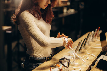 Portrait of happy smiling woman shopping a new smart watch in tech store. Technology people concept