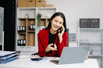 Asian Business woman Talking on the phone and using a laptop with a smile while