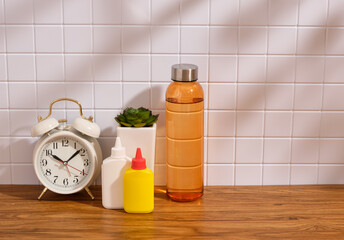 A water shaker, glue, a plant and a vintage alarm clock. Copy space for text.