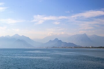 Tranquil seascape with distant mountain range, clear blue sky, and serene atmosphere