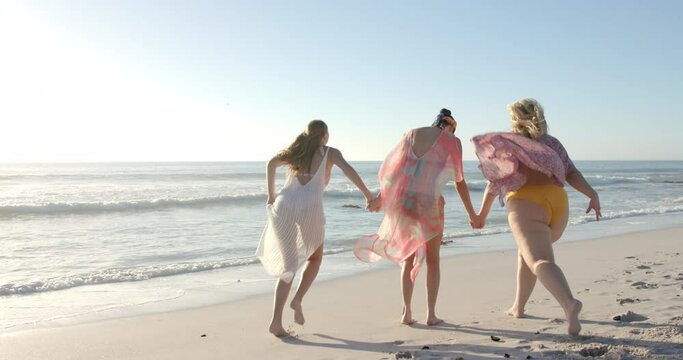 Three women enjoy a carefree run along the beach, with copy space