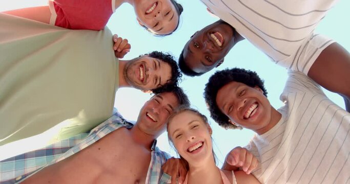 Diverse group of friends smile in a huddle outdoors