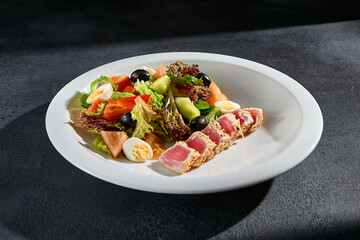 Seared tuna Niçoise salad on a modern dark background; a fresh and gourmet presentation for health-conscious foodies