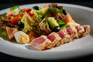 Close-up of Niçoise salad with medium seared tuna on a white plate