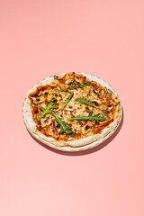 Gluten-free pizza with mushrooms and tomatoes on a stylish plate with a pink backdrop
