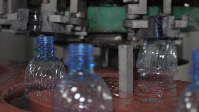 Close up. Empty blue plastic bottles are moved on a conveyor belt. Mineral water production plant.
