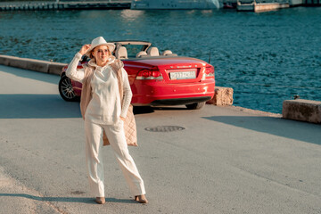 Portrait of a blonde convertible. Fashionable attractive woman with blond hair in a white hat on...