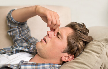 Man, nose and headache pain on sofa or sinus problem with fatigue or allergy infection, sick or...