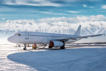White passenger airliner on the airport apron at winter on the background of high picturesque...