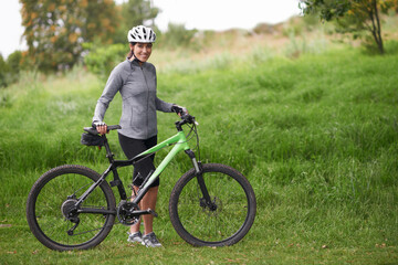 Portrait, smile for cycling and woman in countryside with bike for off road training, cardio or...