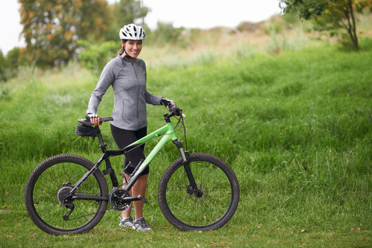 Portrait, smile for cycling and woman in countryside with bike for off road training, cardio or hobby. Exercise, fitness or sports and happy young athlete or cyclist in nature with helmet for workout