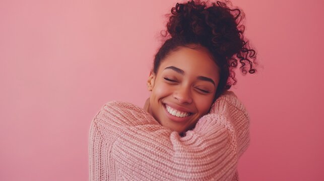 Lovely brunette lady in casual attire on a pink backdrop embracing oneself with a joyful, self-assured smile. Self-love and self-care.