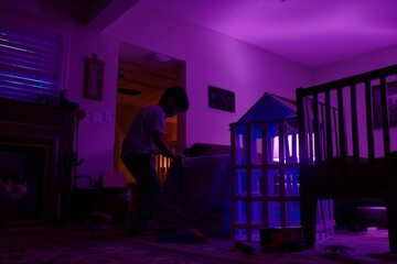 kid building a fort, living room basked in violet glow