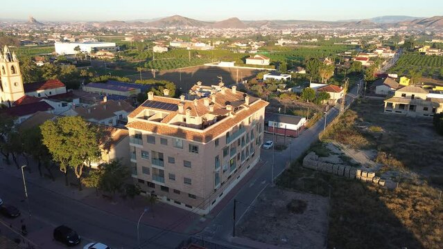 Aerial view of a three floor building at main street in Santa Cruz, Spain. Atics and flats are seeing against the road and the cityscape in the background.